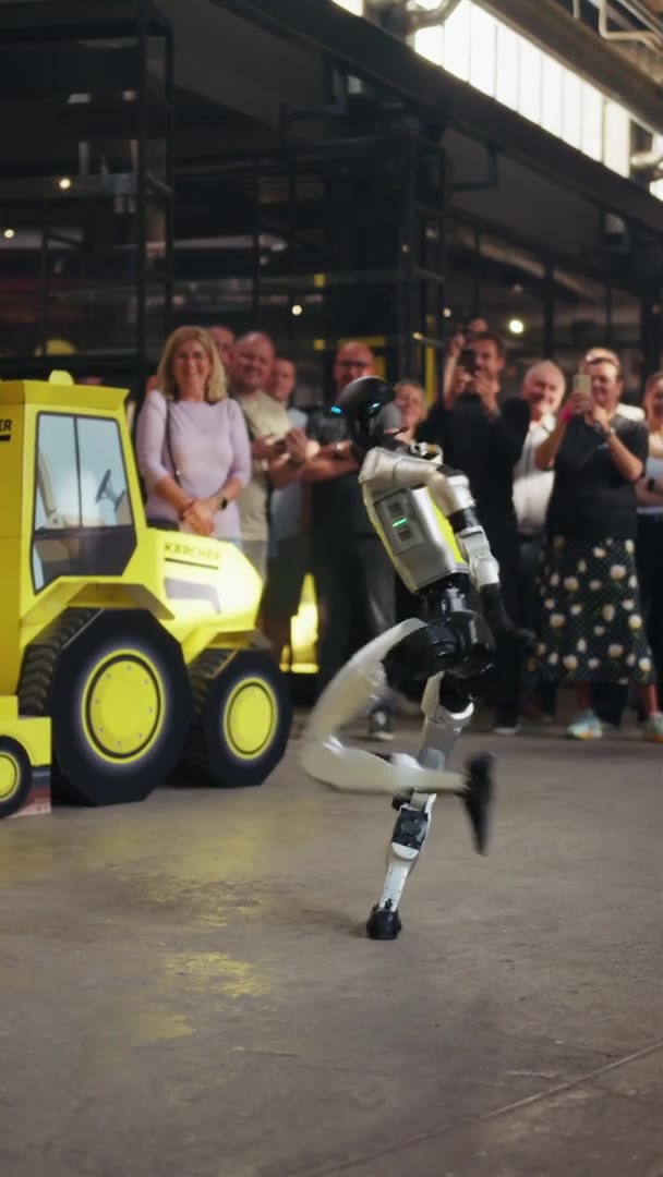 Humanoid robot in KÄRCHER branding dancing in an industrial hall while guests applaud